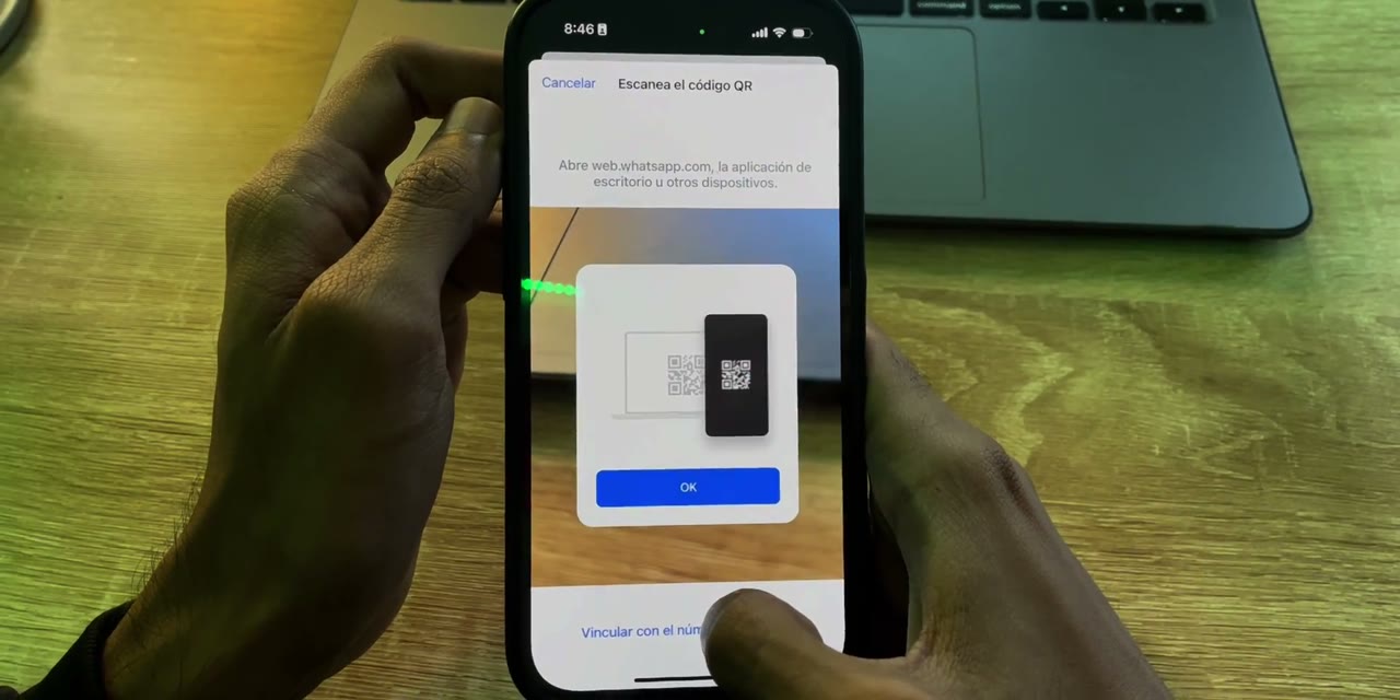 iPhone con la cámara de WhatsApp para escanear el QR y la opción Vincular con el número de teléfono abajo